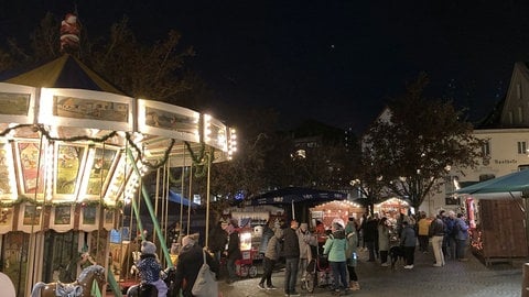 Ein Kinderkarussel steht neben weihnachtlichen Hütten auf dem Wieslocher Weihnachtsmarkt