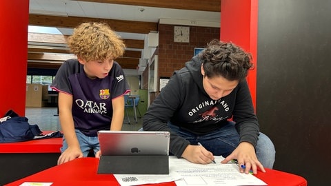 Die Schüler Yunis und Jamal mit Tablet im einer Sitzecke im Geografieunterricht