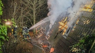 Rauch schlägt aus dem Haus, Feuerwehrleute löschen.