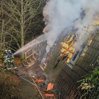 Rauch schlägt aus dem Haus, Feuerwehrleute löschen.