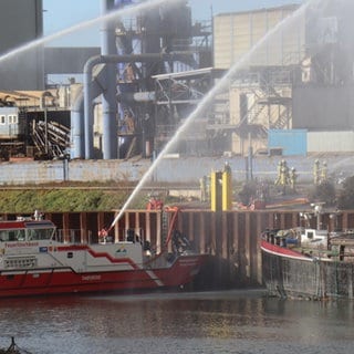 Auch ein Feuerlöschboot ist bei dem Brand im Industriehafen in Mannheim im Einsatz.