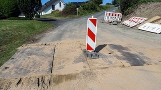 Stahlplatten auf einer Strasse mit Warnbake (Symbolbild)