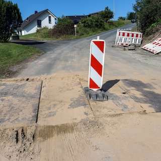 Stahlplatten auf einer Strasse mit Warnbake (Symbolbild)