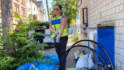 Sauberkeitsermittlerin Sabrina Brand zieht sich die Handschuhe an, um Müll im Stadtteil Waldhof zu untersuchen