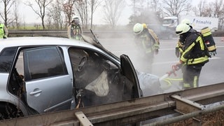 Retter der Feuerwehr löschen ein brennendes Auto auf der A5 bei St. Leon-Rot.