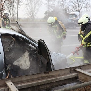 Retter der Feuerwehr löschen ein brennendes Auto auf der A5 bei St. Leon-Rot.