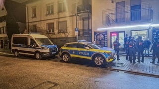 Polizeibeamte und Streifenwagen stehen vor einem Geschäft für Goldankauf