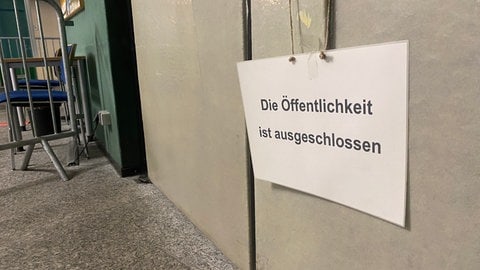 An einer Tür hängt ein Schild mit der Aufschrift "Die Öffentlichkeit ausgeschlossen".