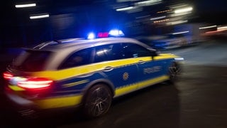 Ein Polizeifahrzeug fährt mit Blaulicht an einem Gebäude vorbei (Symbolbild). 