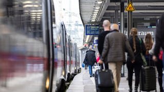 Menschen laufen mit Koffern am Stuttgarter Hauptbahnhof zu einem ICE