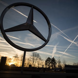 Die Sonne geht hinter einem Mercedes-Stern auf dem Mercedes-Benz-Werk auf.