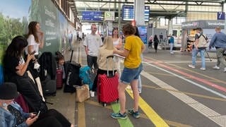 Eine Gruppe Reisender wartet auf dem Stuttgarter Hauptbahnhof.