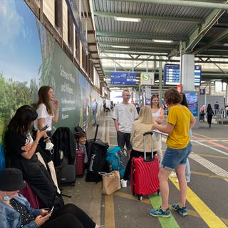 Eine Gruppe Reisender wartet auf dem Stuttgarter Hauptbahnhof.