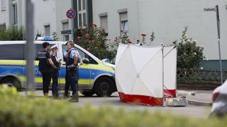 Einsatzkräfte der Polizei neben dem abgeschirmten Tatort in Ludwigsburg. Dort wurde am Dienstag ein 79-jähriger Mann erstochen.