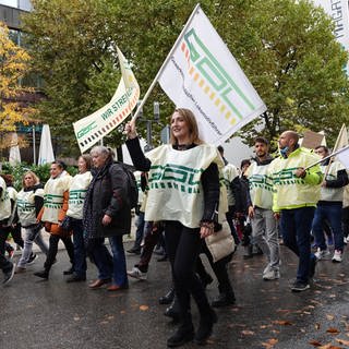 Bei einer Protestaktion der Lokführergewerkschaft GDL in Stuttgart gehen Menschen über eine Straße. Die Gewerkschaft protestierte am Freitag für einen Konzerntarifvertrag bei der landeseigenen Südwestdeutschen Landesverkehrs-GmbH (SWEG).