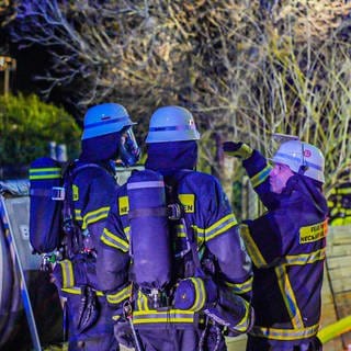 Feuerwehrleute mit Atemschutzausrüstung besprechen sich vor ihrem Einsatz bei einem Brand in Neckartailfingen.