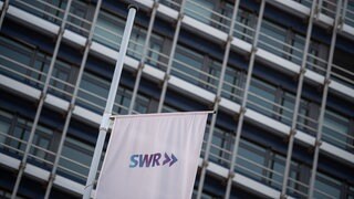 Wehende, weiße Flagge mit SWR-Aufdruck, im Hintergrund graue Fassade des Stuttgarter Funkhauses.