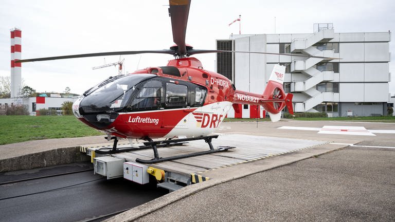 Ein Rettungshubschrauber steht auf dem Helikopterlandeplatz der Station Leonberg der DRF Luftrettung, im Hintergrund ist das Krankenhaus Leonberg zu sehen. 