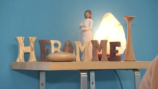 Eine schwangere Frau und das Wort Hebamme sind auf einem Tisch nachgebildet.