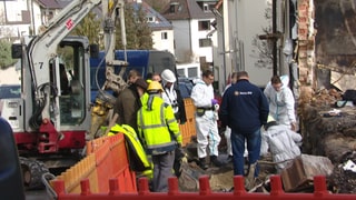 Ermittler untersuchen Leitungen im  Boden vor dem explodierten Haus. 