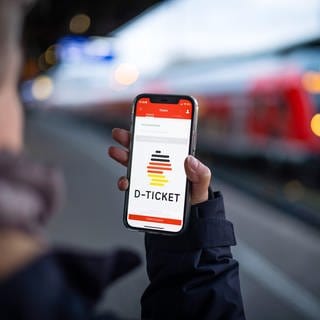 Eine Frau schaut am Bahnsteig auf das Deutschlandticket in ihrer Smartphone-App: Ab dem 1. Mai gilt im Nah- und Regionalverkehr das neue Angebot.