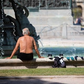 Ein Mann kühlt sich bei heißen Temperaturen an einem Brunnen in der Stuttgarter Innenstadt ab.
