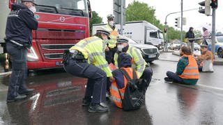 Polizisten tragen einen Demonstranten der Aktivistengruppierung "Letzte Generation" weg, der eine Hauptverkehrsstraße in Stuttgart blockiert hat