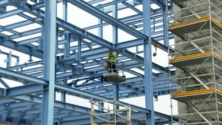 Ein Mann montiert etwas in luftiger Höhe in einem Neubau eines Gas-Werkes der EnBW.