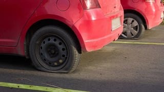 Zwei rote Autos mit platten Reifen.
