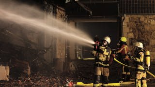 Feuerwehrleute löschen an einem Brand in einer Scheune auf einem Pferdehof. Beim Vollbrand am Sonntagabend kamen keine Menschen oder Tiere zu Schaden, wie die Polizei mitteilte.