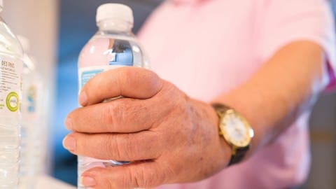 Seniorin greift nach Wasserflasche 