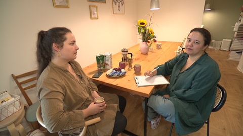 Die Hebammen Nathalie Rose (links) und Janna Hufnagel sitzen an einem Holztisch in ihrem Geburtshaus "Amma" in Aichtal: Der Bau hat den beiden viel Kraft und noch mehr Nerven abverlangt.