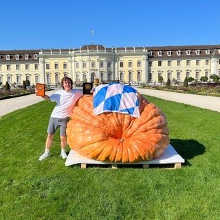 Der Sieger-Kürbis vor dem Schloss Ludwigsburg neben seinem Züchter Luca Stöckl aus Bayern: Der Atlantic-Giant brachte erstmals mehr als eine Tonne Riesenkürbis auf die Waage. 