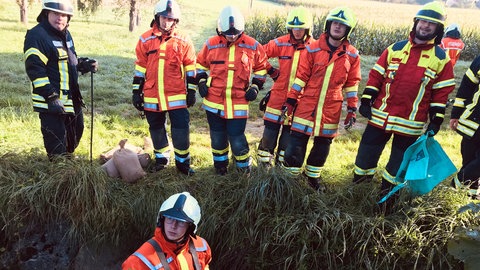 Nico Schieszl baut im Söllbach bei Burgstetten (Rems-Murr-Kreis) bei einer Übung eine Ölsperre aus Sandsäcken. Die Kameraden beobachten jeden Handgriff des jungen Feuerwehrmanns.