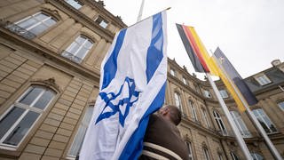 Ein Mitarbeiter des Staatsministeriums hisst eine Israel-Flagge.