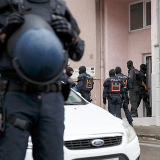 Polizisten stehen bei einer Razzia vor einem Hauseingang in Stuttgart (Archivbild). 