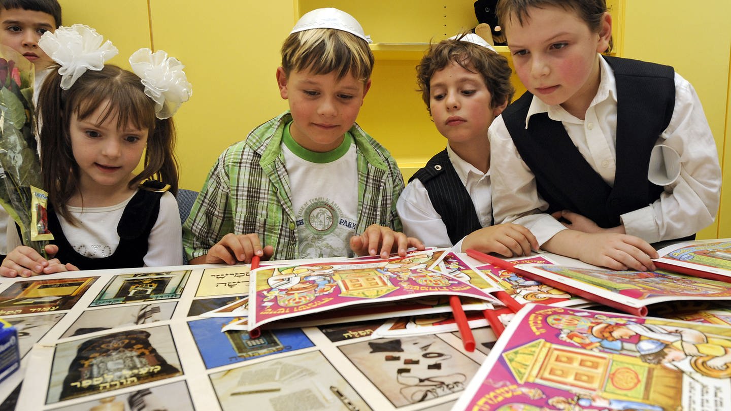 Jüdische Schüler betrachten während der Eröffnung der jüdischen Grundschule in Stuttgart bedruckte Papierbögen.
