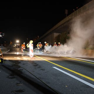 Rettungskräfte begutachten ein ausgebranntes und aus dem Dach liegendes Auto nach einem Unfall auf der B10 bei Ebersbach im Kreis Göppingen.