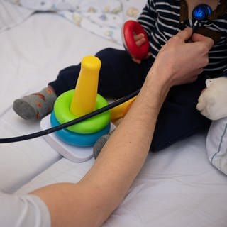 Ein Arzt im Olgahospital Stuttgart untersucht ein Kleinkind (Archivbild).