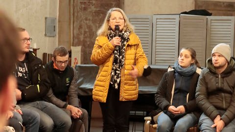 Pfarrerin Gabriele Ehrmann bei der Vesperkirche 2023 in einer Runde mit Besucherinnen und Besuchern. Sie sagt: "Wir wollen, dass niemand arm sein muss."
