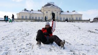 Eine junge Frau fährt am Schloss Solitude Schlitten. 