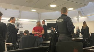 Mehrere Angeklagte stehen im Saal des Stuttgarter Landgerichts und warten auf die Urteilsverkündung.