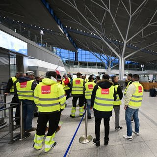 Streikende Mitarbeiter des Flughafens Stuttgart stehen am 17. März 2023 mit Westen der Gewerkschaft ver.di in der leeren Abflughalle.