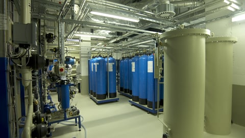 In der neue Abklinganlage im Klinikum Stuttgart wird das radioaktive Material gereinigt. Große laue und beige Tanks stehen in einem Raum voller Rohre.