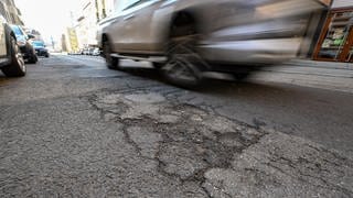 Geparkte Autos und ein fahrendes Auto in Stuttgart. (Archivbild)