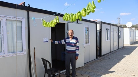 Ein Mann steht vor einem Container, der zu einem Containerdorf gehört, das nach dem Erdbeben von STELP in der Türkei errichtet wurde.