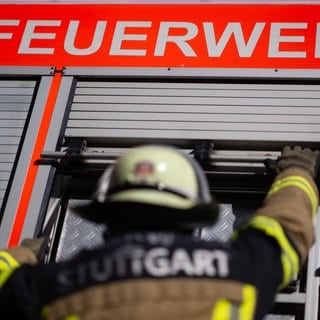 Ein Feuerwehrmann schließt einen Bereich eines Einsatzfahrzeugs.