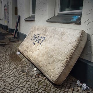 eine ausrangierte Matratze mit der Aufschrift "Müde?" auf einem Gehweg einer Großstadt (Archivbild)