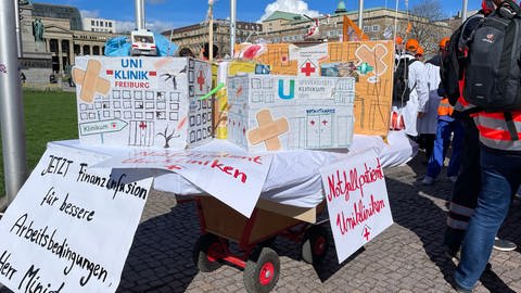 "Notfallpatient Uniklinikum" steht auf einer improvisierten Krankenliege, die symbolisch für alle Unikliniken des Landes stehen soll.