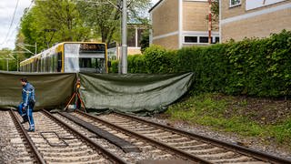 Eine Stadtbahn steht an einer Haltestelle in Stuttgart. Die tödliche Unfallstelle wurde von den Rettungskräften mit einer grünen Plane abgeschirmt. 